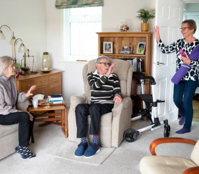 A sitter greets a carer and cared-for before the start of a Carers Break