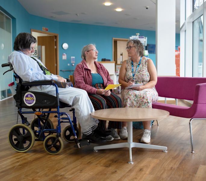 A carer support office having a discussion in a hospital with a carer and their cared-for