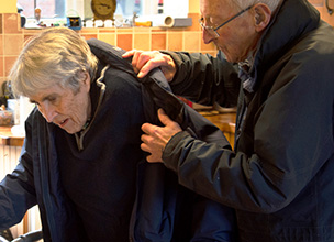 Man helping older woman take off her coat